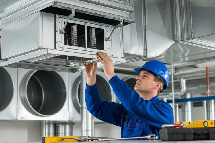 Professional installation of a fire damper in a ventilation system, technician adjusting frame.